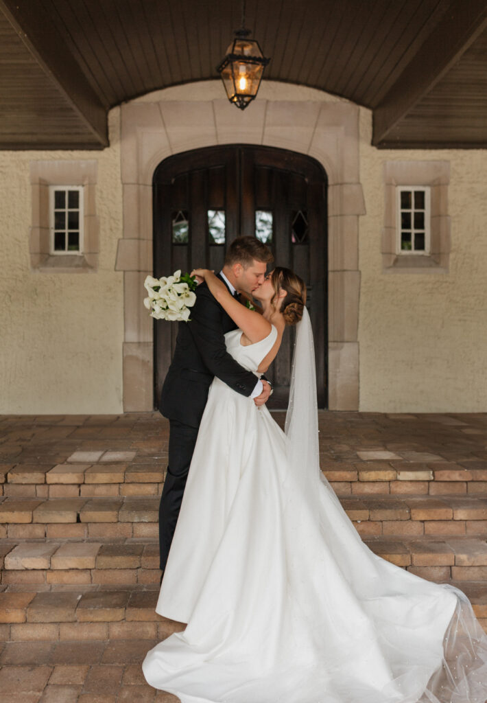 bride and groom kissing infront of door to wedding reception