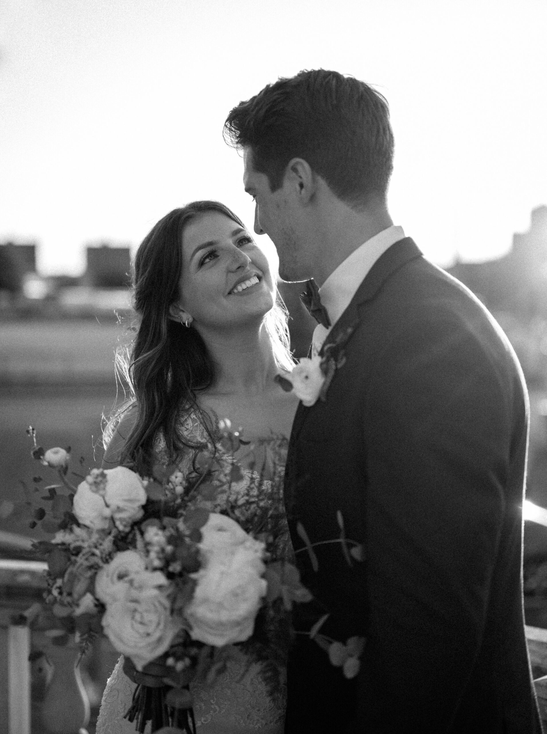 black and white photo of bride and groom staring lovingly at each other in the sunset