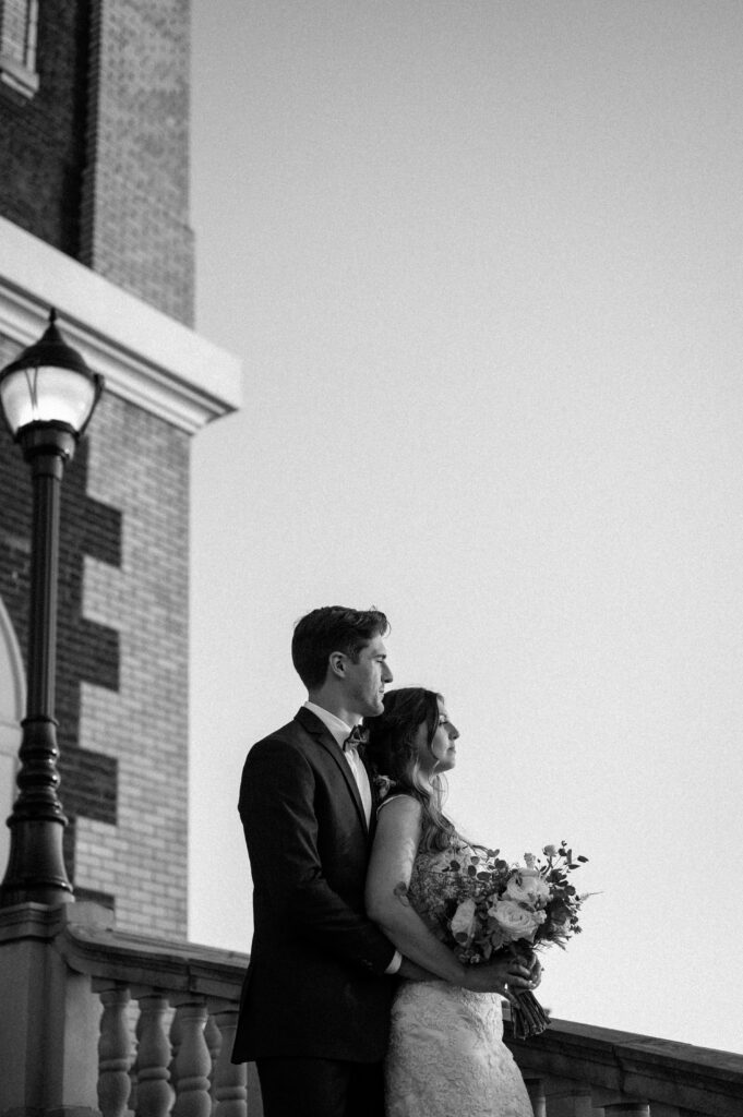 bride and groom looking out in the world holding each other close in black and white 