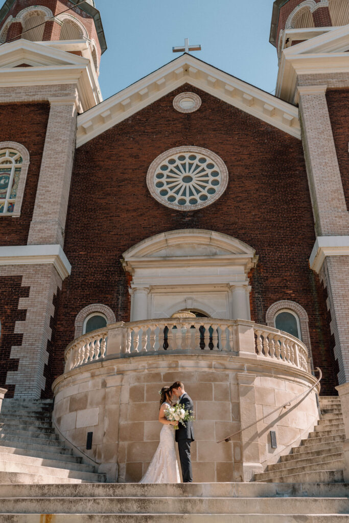 bride and groom in front of church during the day at water's edge event centre