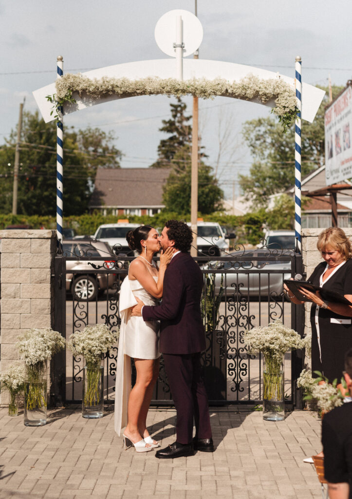 bride and groom kissing at the end of their ceremony surrounded by baby's breath on the terrace at the heimat restaurant