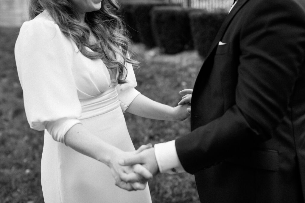 Bride and groom holding hands outside in black and white