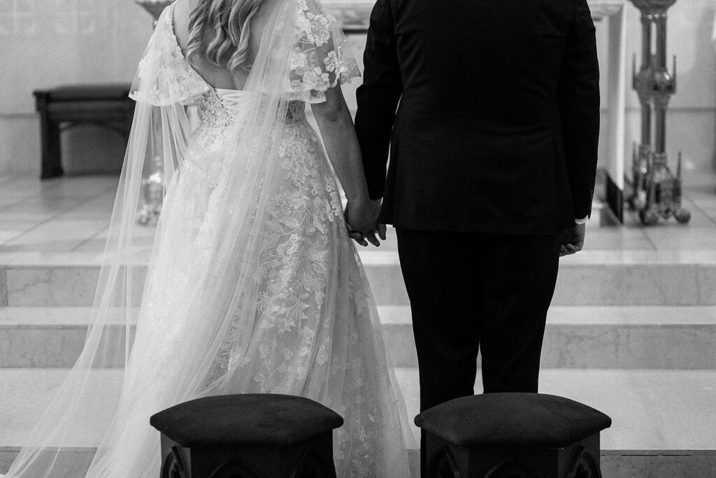 church ceremony black and white photo, bride and groom holding hands 